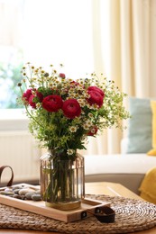 Photo of Beautiful ranunculus flowers and chamomiles in vase on table indoors