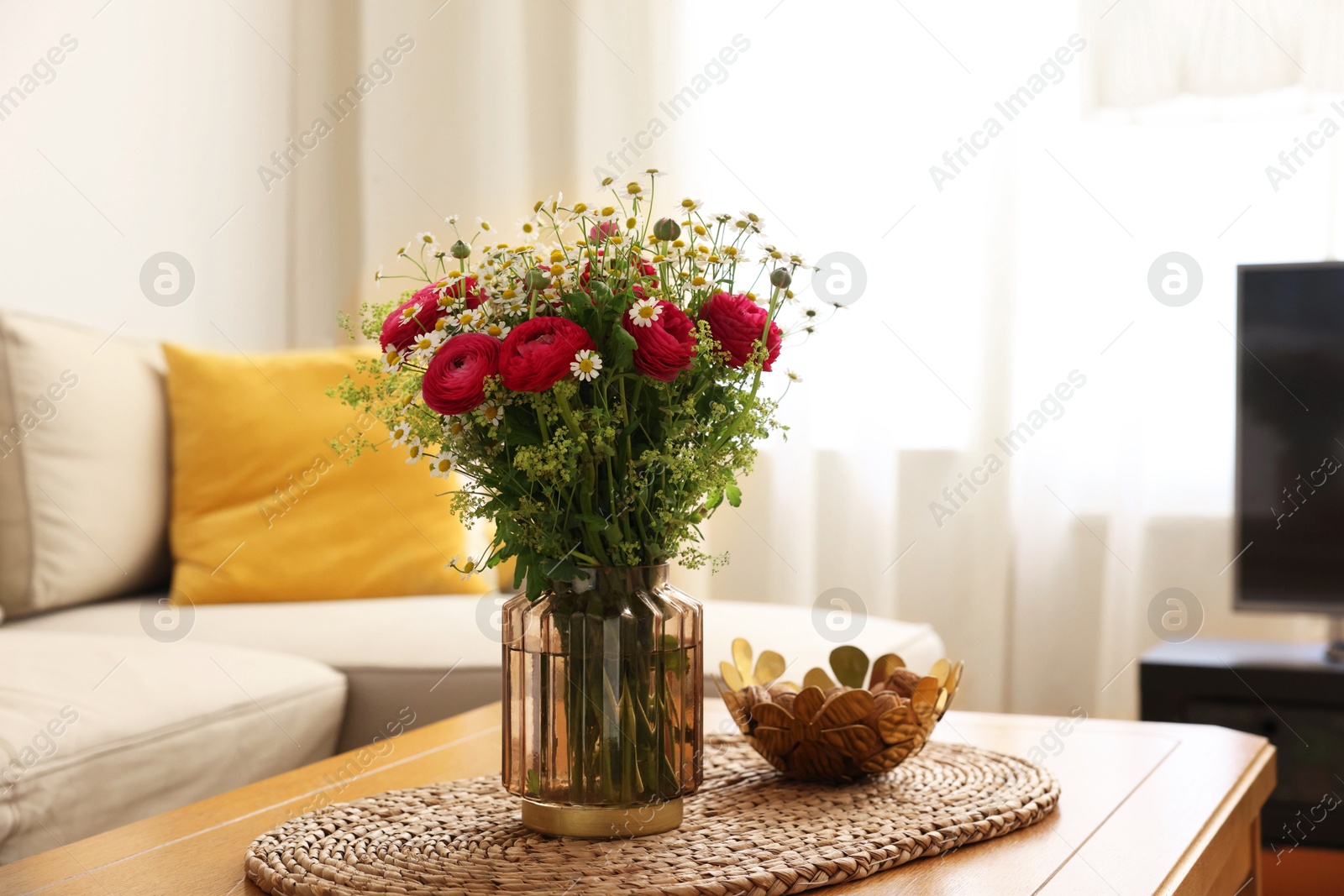 Photo of Beautiful ranunculus flowers and chamomiles in vase on table indoors