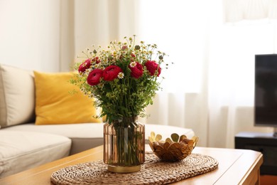 Beautiful ranunculus flowers and chamomiles in vase on table indoors