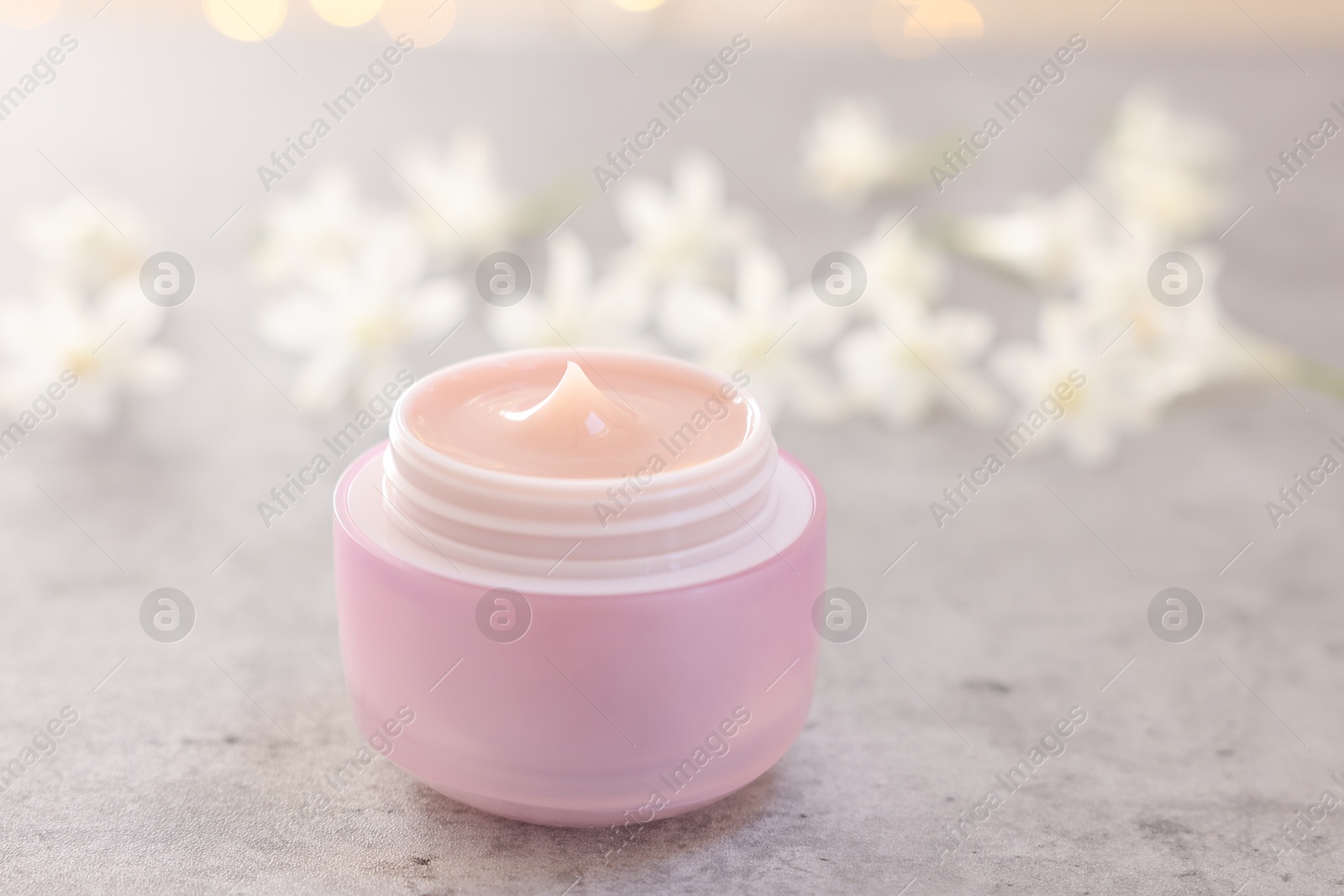 Photo of Cream in jar on grey table, closeup. Cosmetic product