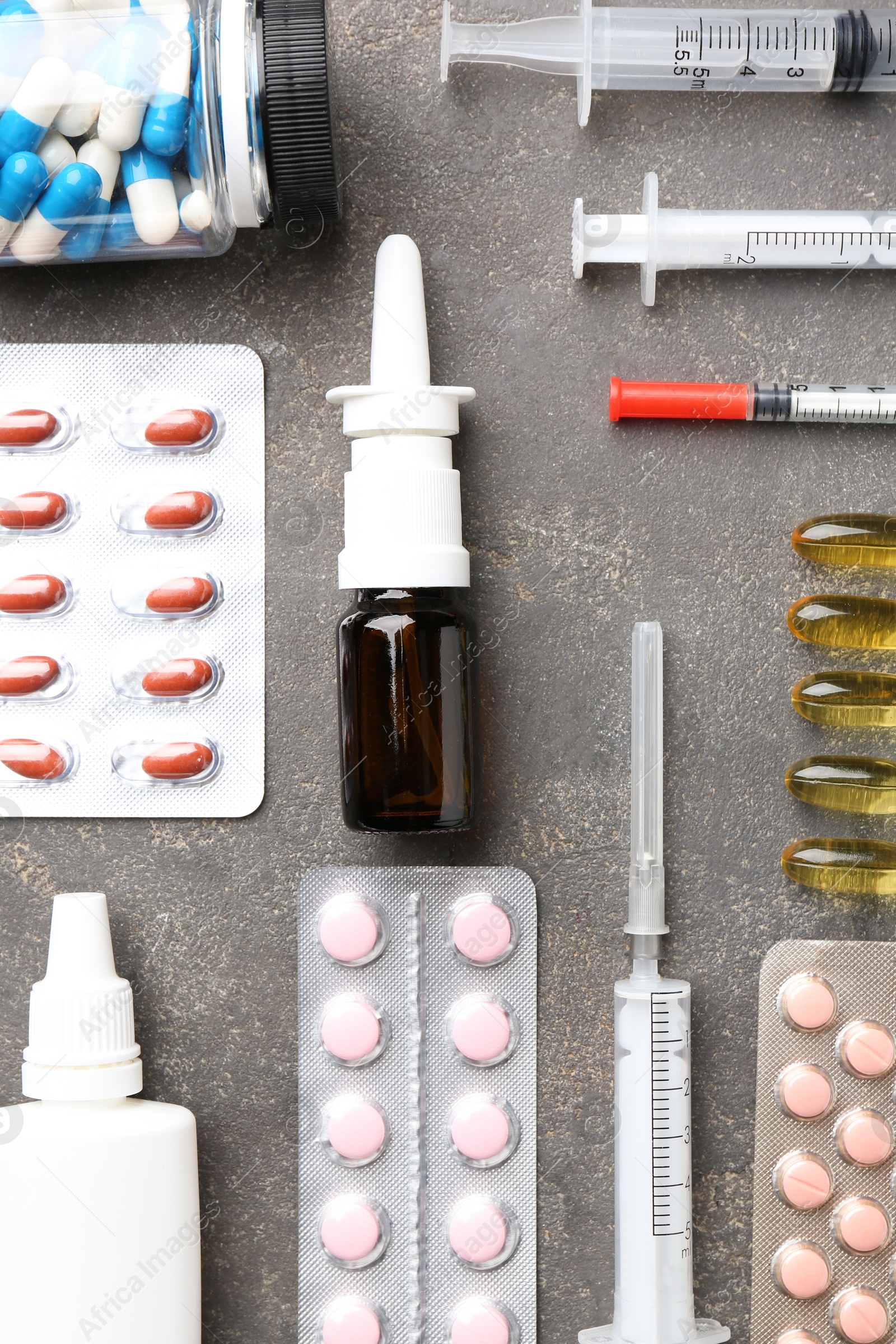 Photo of Pharmacist. Different pills, syringes and bottles of medical drops on grey table, flat lay