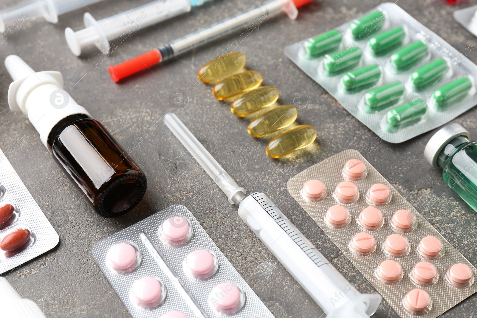 Photo of Pharmacist. Different pills, syringes and bottle of medical drops on grey table, closeup