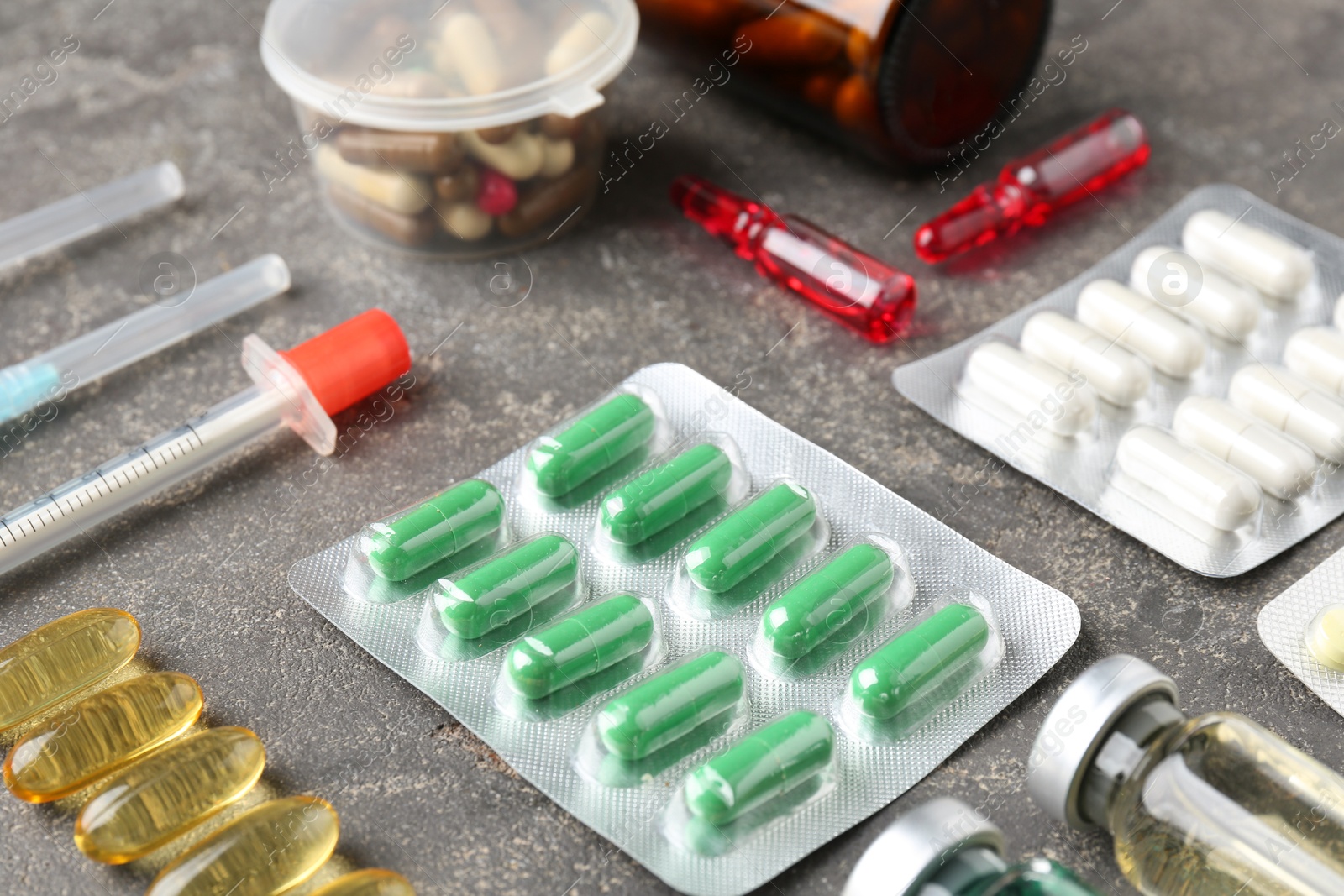 Photo of Pharmacist. Different pills, syringes and ampoules on grey table, closeup