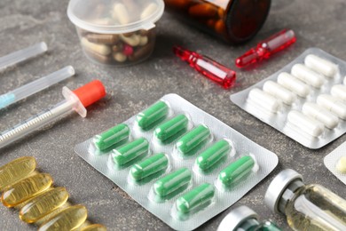 Pharmacist. Different pills, syringes and ampoules on grey table, closeup