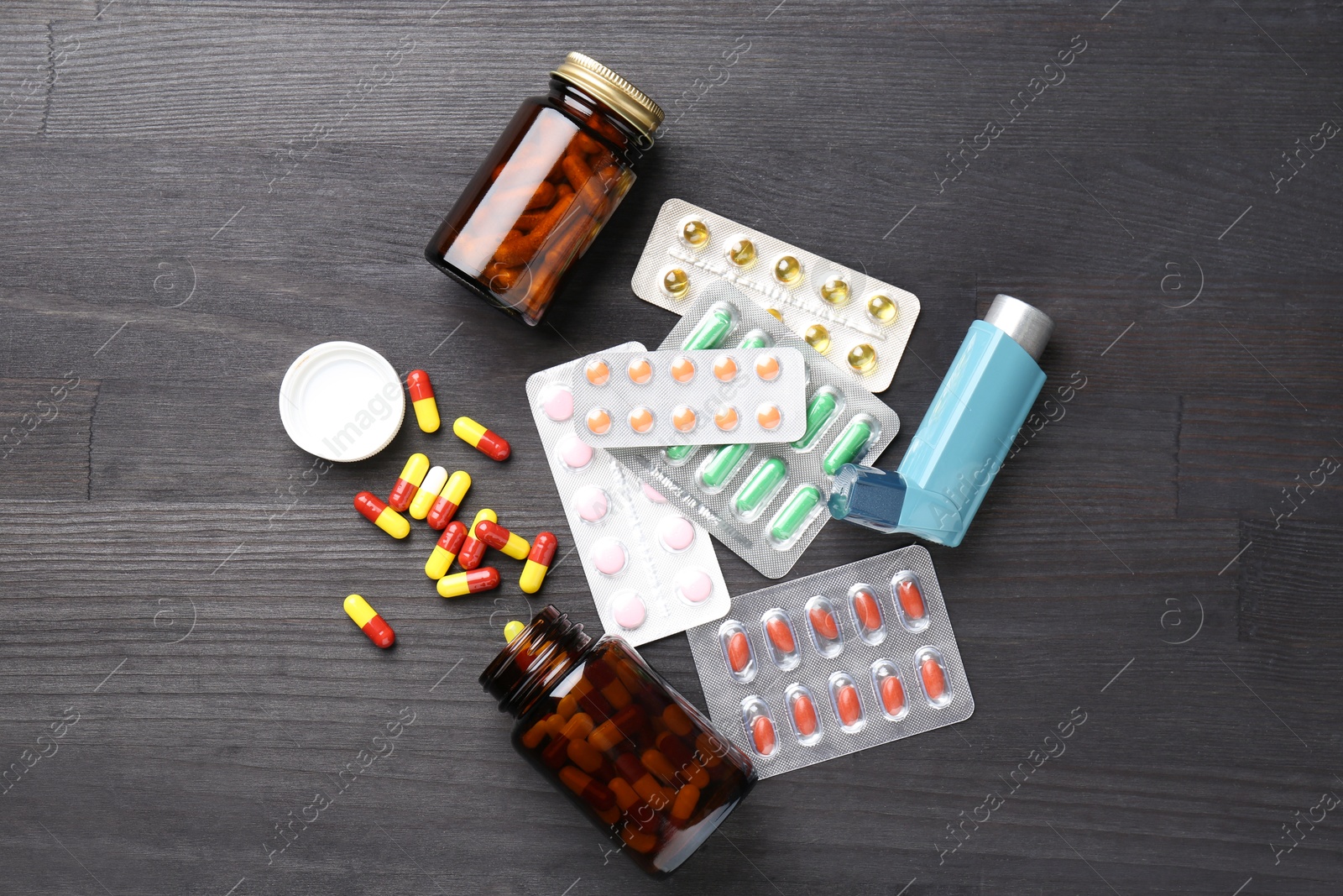 Photo of Pharmacist. Different pills and inhaler on grey wooden table, flat lay