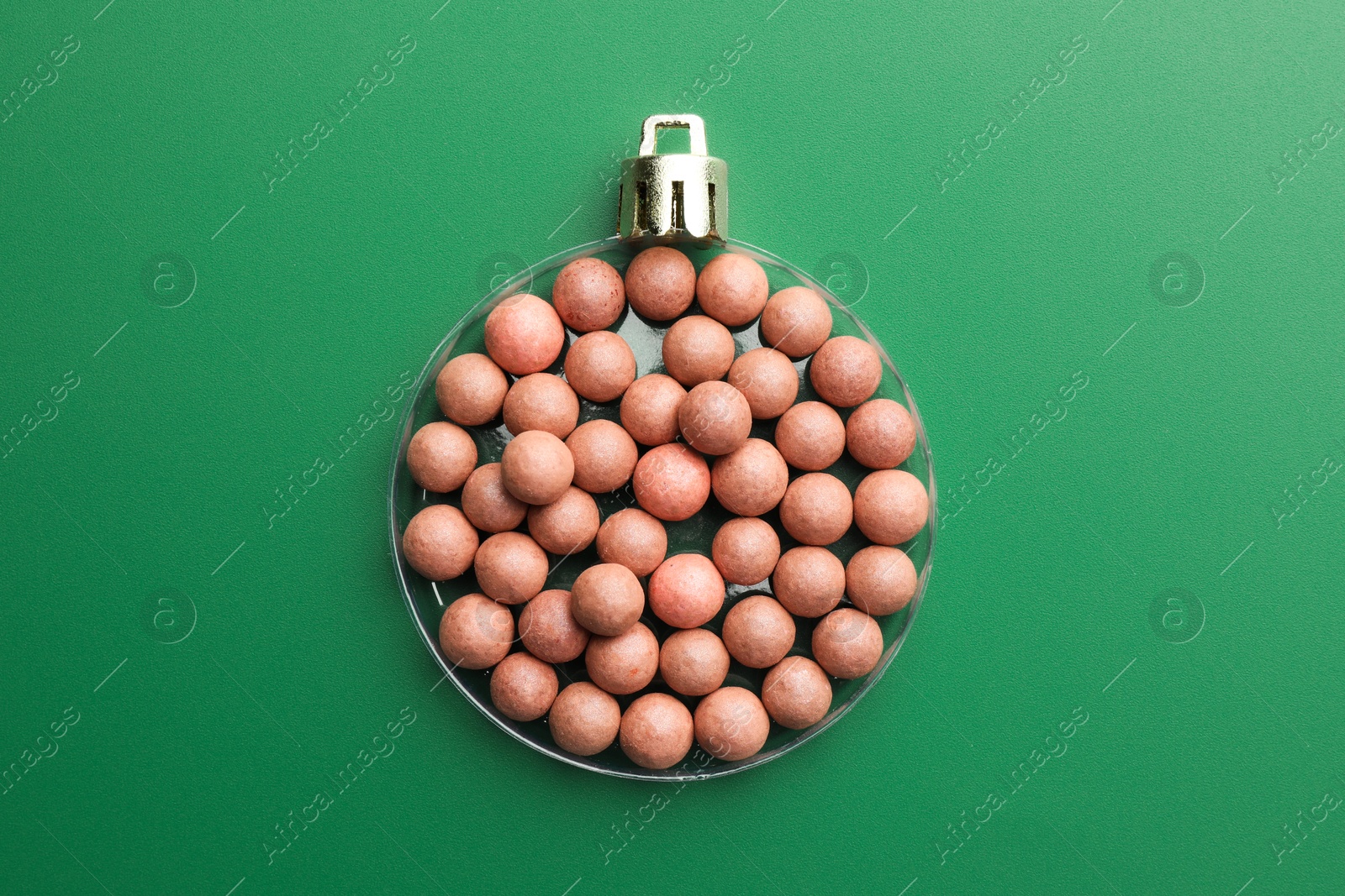 Photo of Christmas ball made of cosmetic product on green background, top view