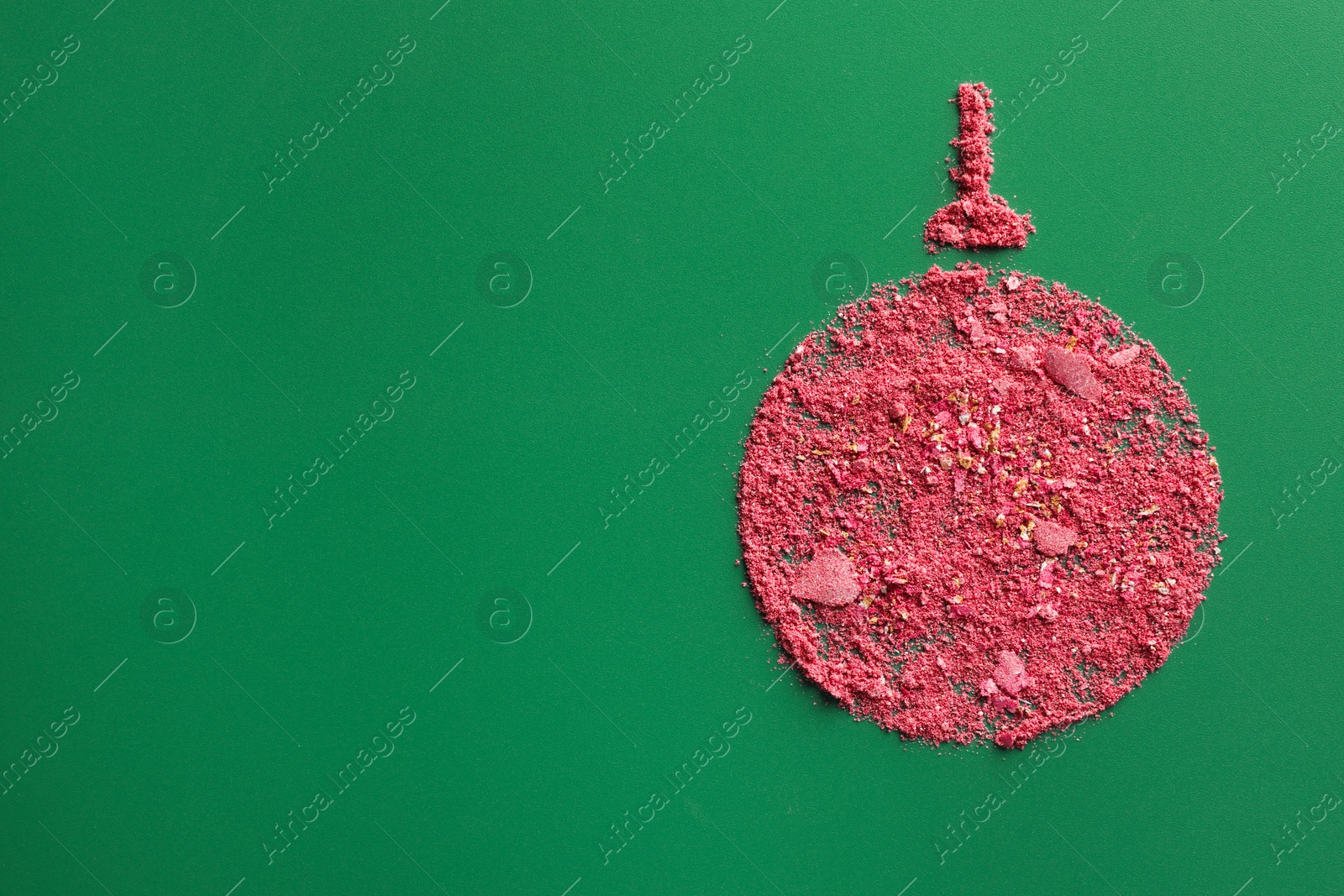 Photo of Christmas ball made of blush on green background, top view. Space for text