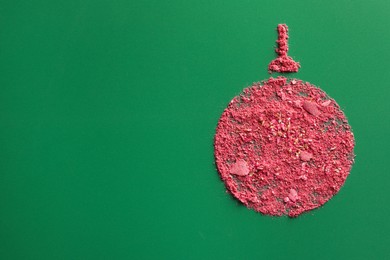 Photo of Christmas ball made of blush on green background, top view. Space for text