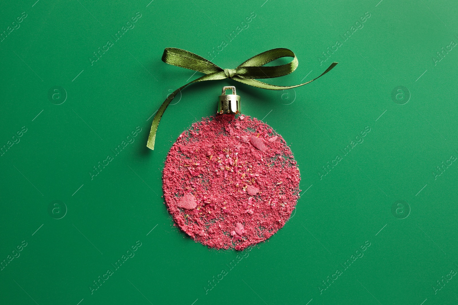 Photo of Christmas ball made of blush and bow on green background, top view