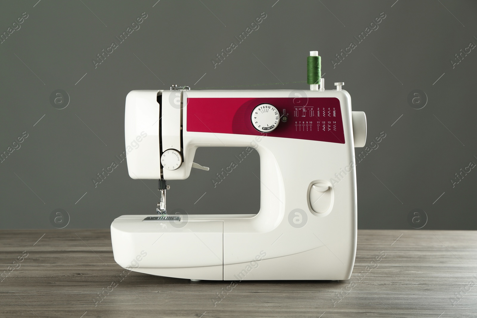 Photo of One sewing machine on wooden table against grey background