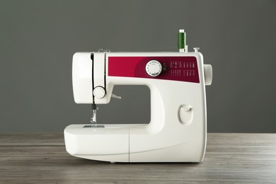 One sewing machine on wooden table against grey background