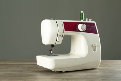 Photo of One sewing machine on wooden table against grey background