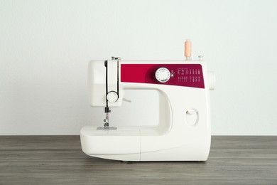 One sewing machine on wooden table against white background