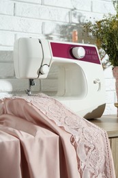 Sewing machine with fabric on wooden table indoors