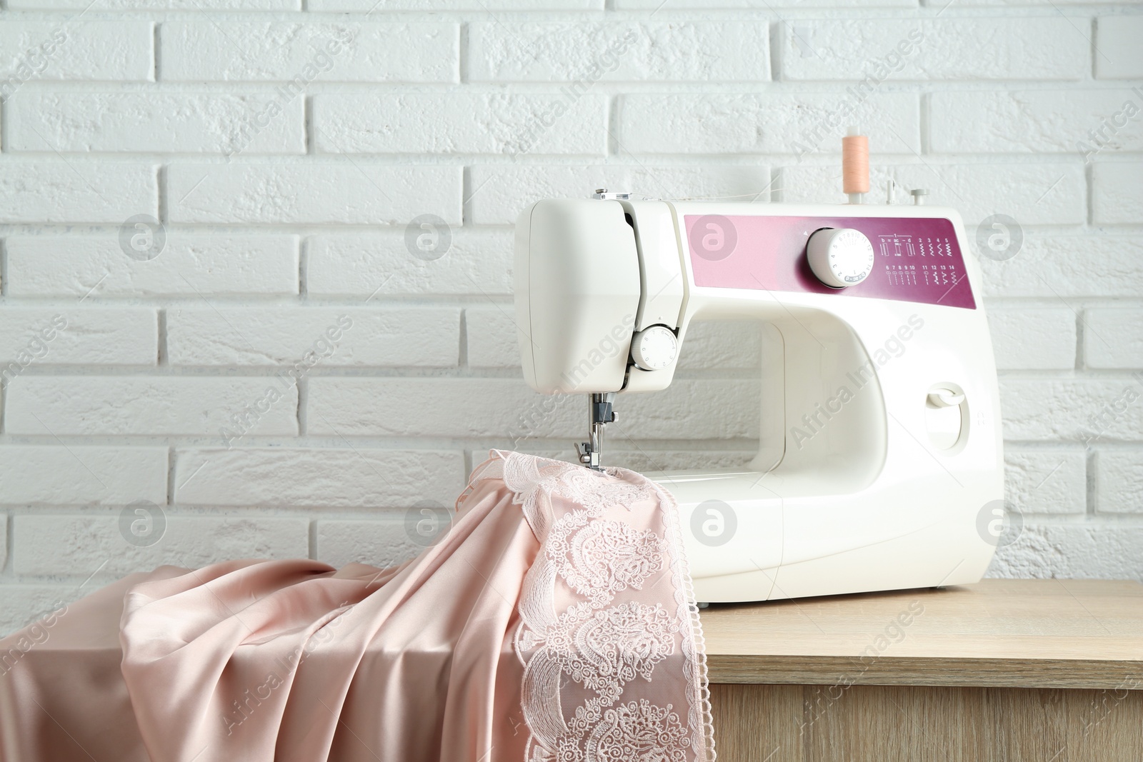 Photo of Sewing machine with fabric on wooden table indoors