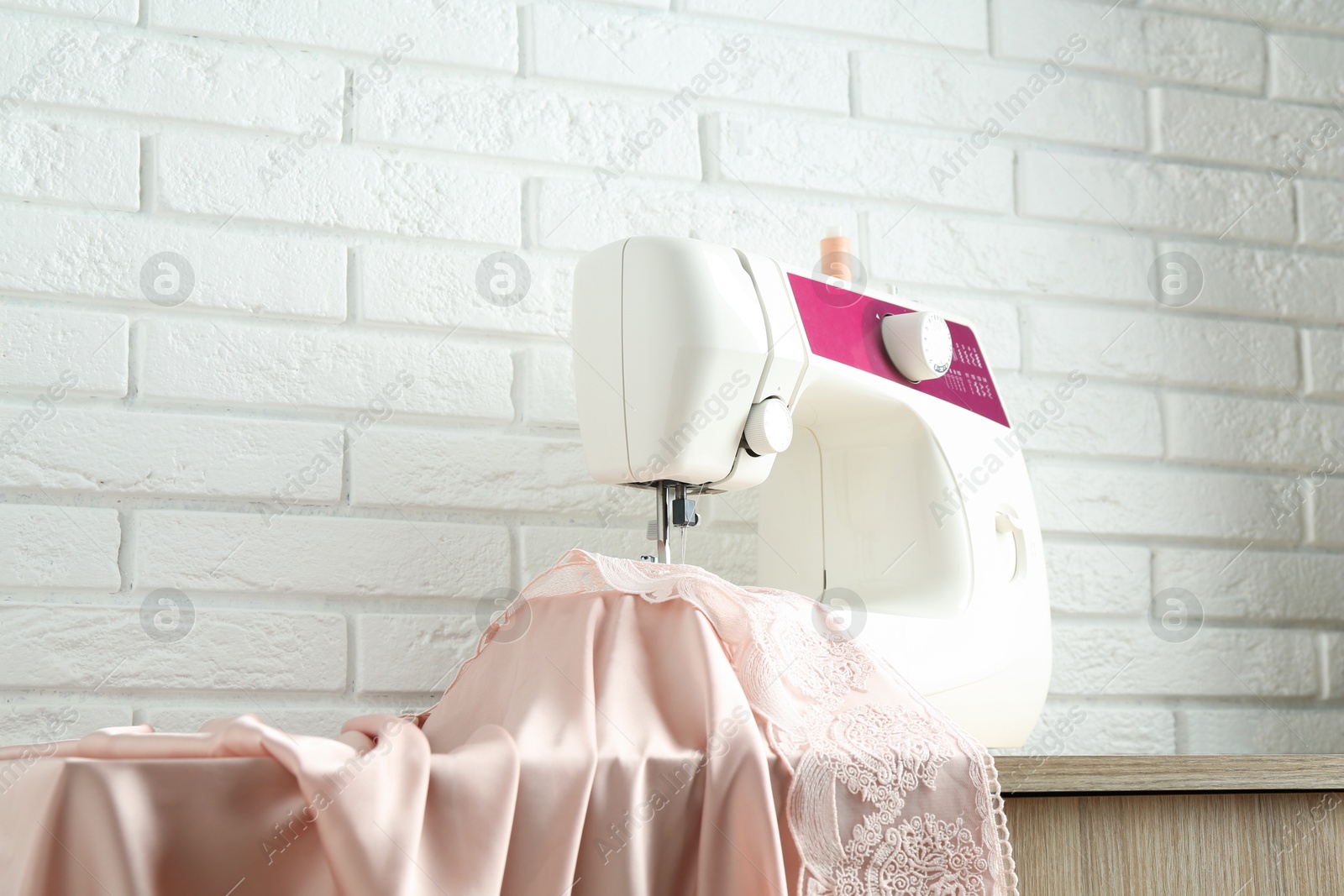 Photo of Sewing machine with fabric on wooden table indoors