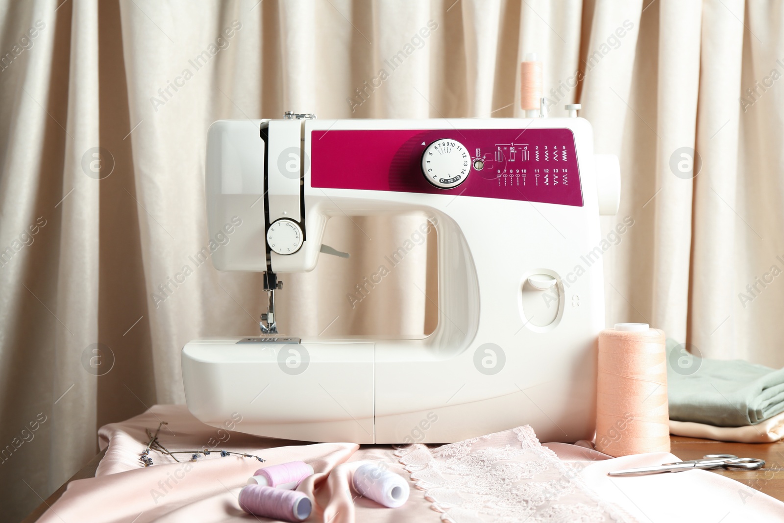 Photo of Sewing machine with fabric and tools on table indoors