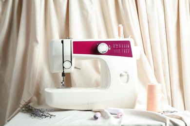 Photo of Sewing machine with fabric and tools on table indoors