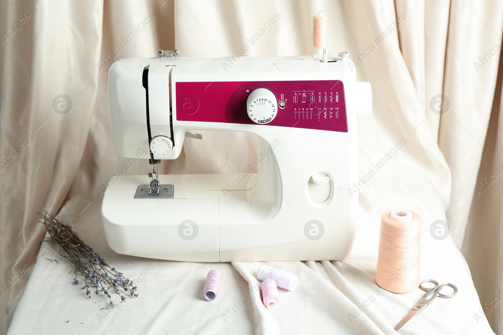 Photo of Sewing machine with fabric and tools on table indoors