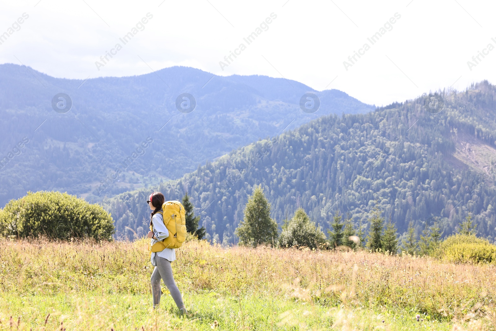 Photo of Young woman with backpack hiking in mountains