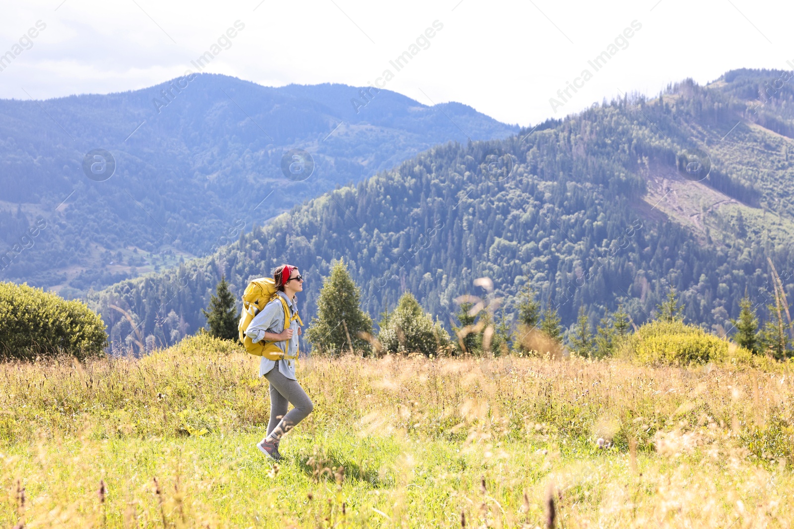 Photo of Young woman with backpack hiking in mountains