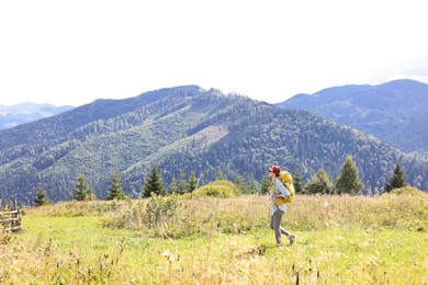 Photo of Young woman with backpack hiking in mountains