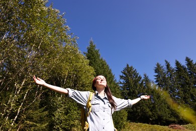 Photo of Young hiker with backpack in mountains, low angle view