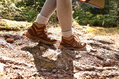 Photo of Young hiker in trekking shoes walking outdoors, closeup