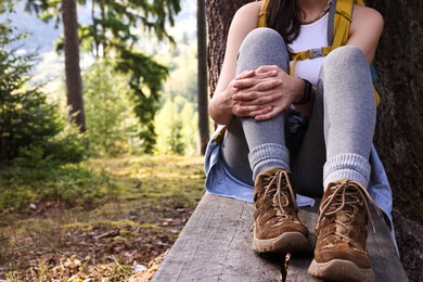 Photo of Young hiker sitting on wooden bench in forest, closeup