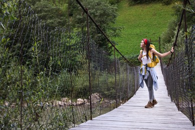 Photo of Young hiker on wooden bridge over river