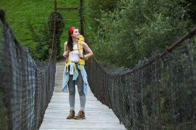 Photo of Young hiker walking on wooden bridge over river