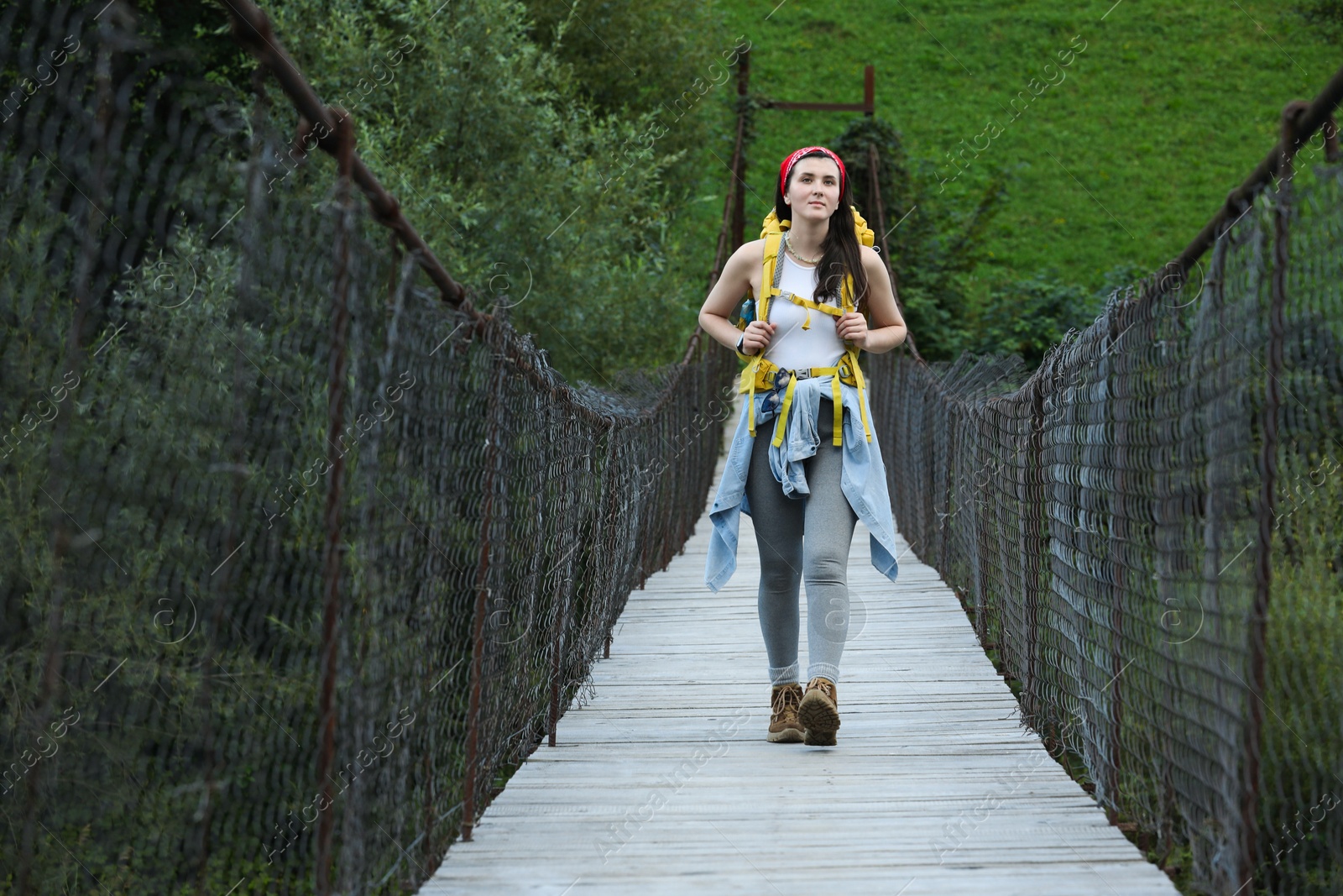 Photo of Young hiker walking on wooden bridge over river