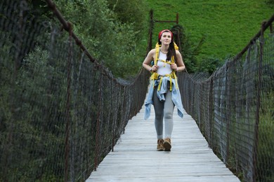 Photo of Young hiker walking on wooden bridge over river