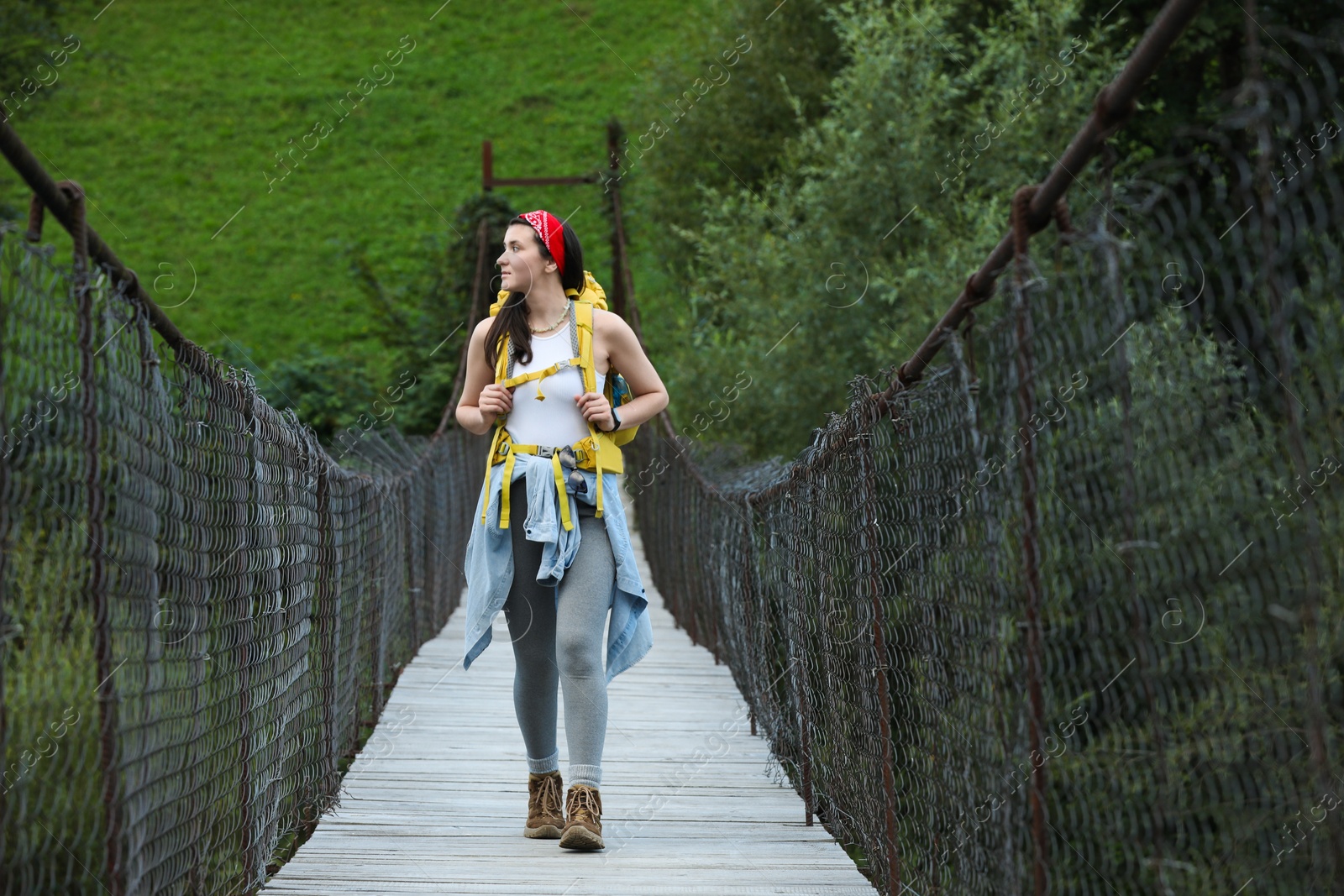 Photo of Young hiker walking on wooden bridge over river