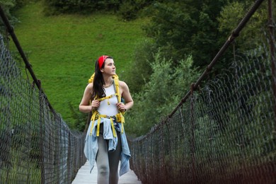 Photo of Young hiker walking on bridge in mountains