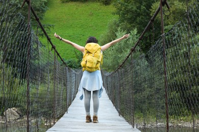 Young hiker on wooden bridge over river