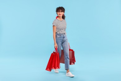 Photo of Smiling woman with shopping bags on light blue background. Space for text