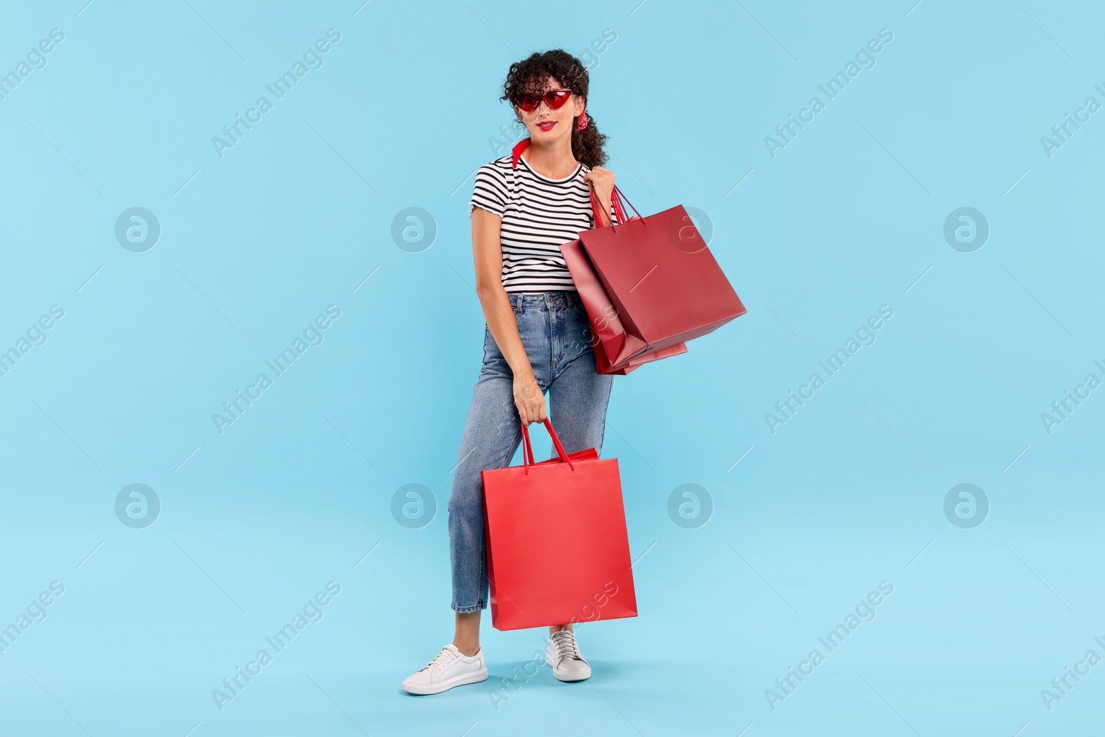 Photo of Beautiful woman with shopping bags on light blue background. Space for text