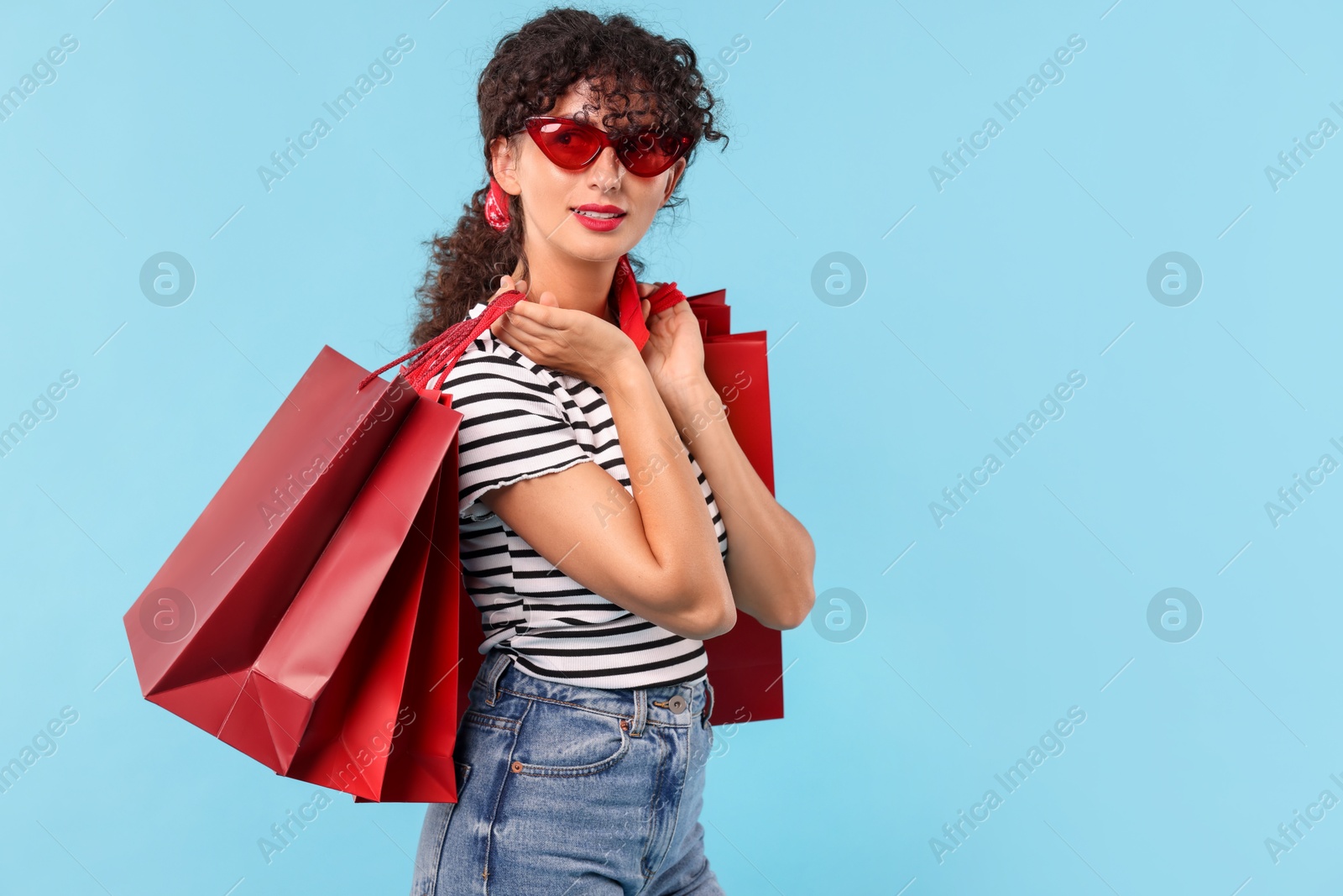 Photo of Beautiful woman with shopping bags on light blue background. Space for text