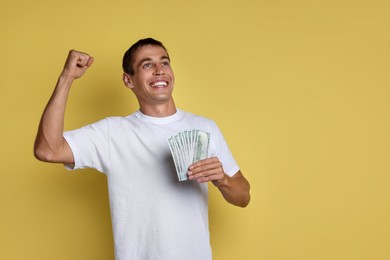 Photo of Happy man with money on yellow background, space for text