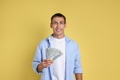 Photo of Happy man with money on yellow background