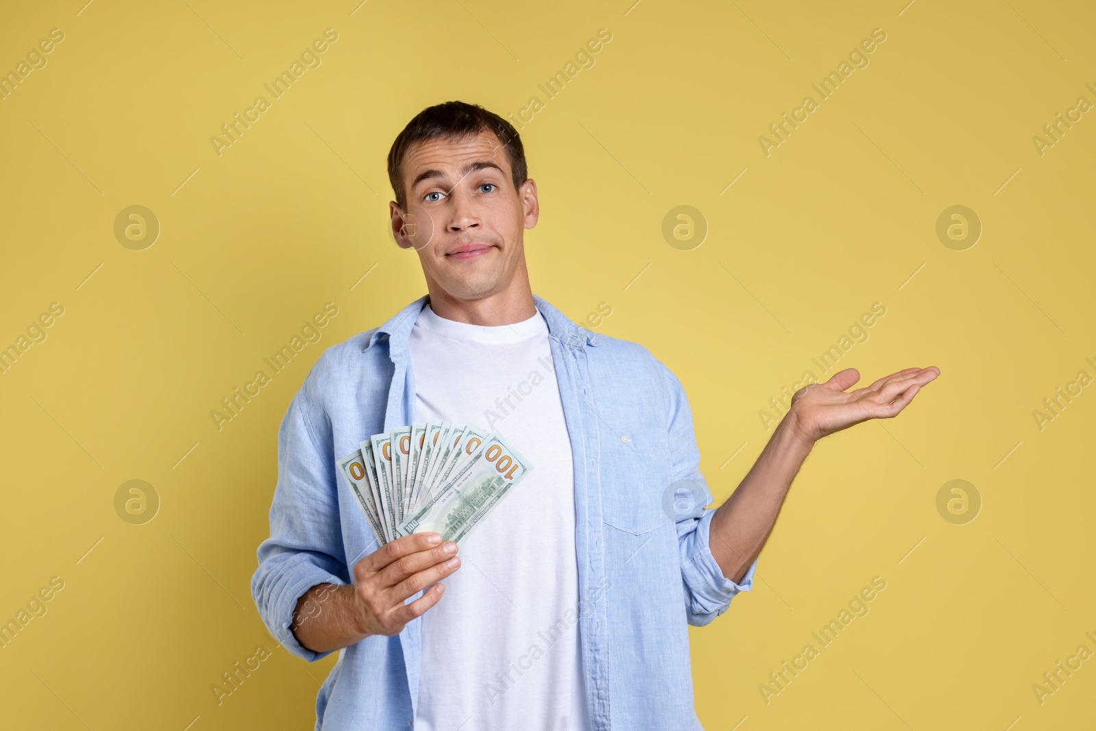 Photo of Man with dollar banknotes on yellow background