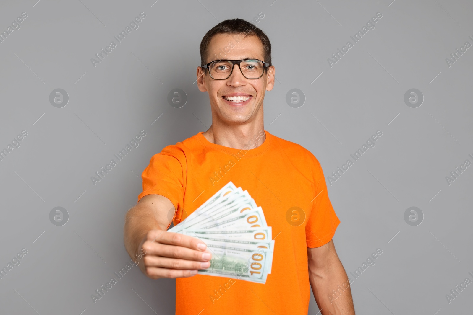 Photo of Happy man with dollar banknotes on grey background