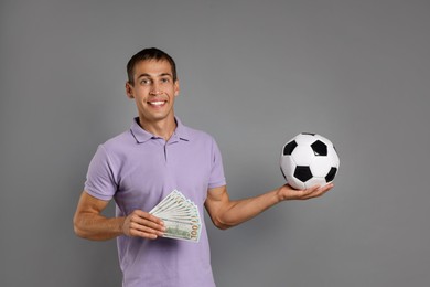 Photo of Man with money and soccer ball on grey background