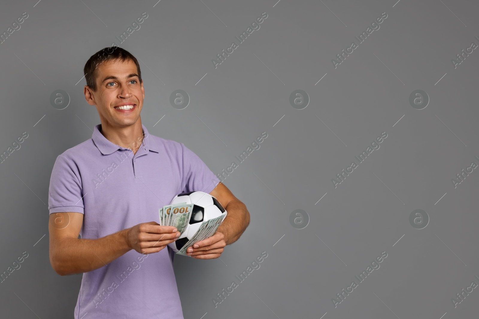 Photo of Man with money and soccer ball on grey background, space for text