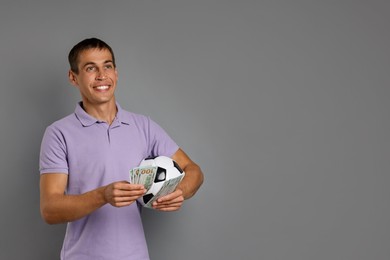 Photo of Man with money and soccer ball on grey background, space for text