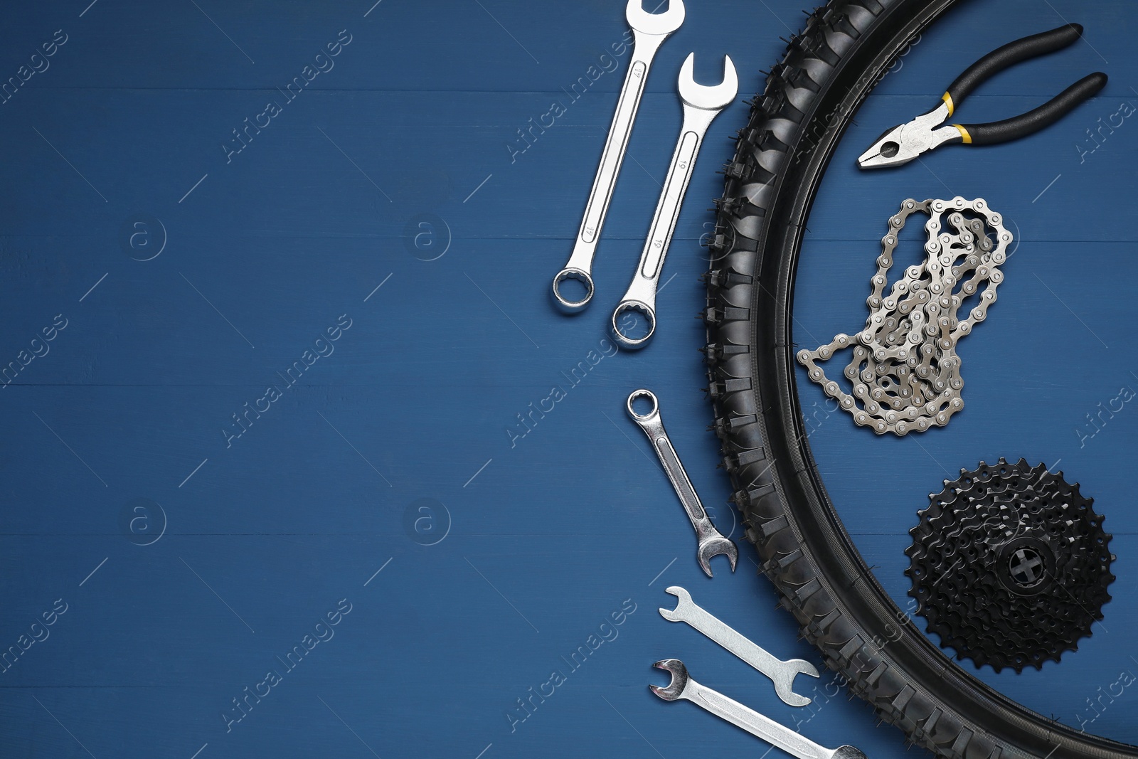 Photo of Parts of bicycle and tools on blue wooden background, flat lay. Space for text