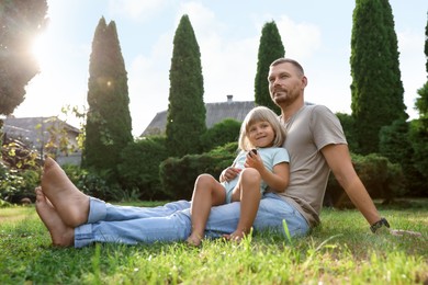 Photo of Father and his daughter spending time together on green lawn in park