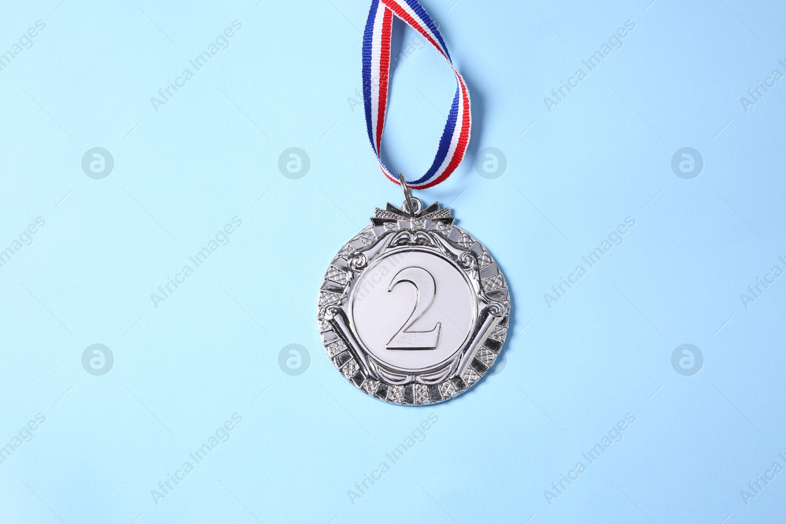 Photo of One silver medal on light blue background, top view