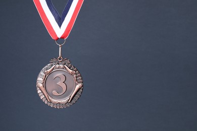 Photo of Bronze medal with striped ribbon on grey background, space for text